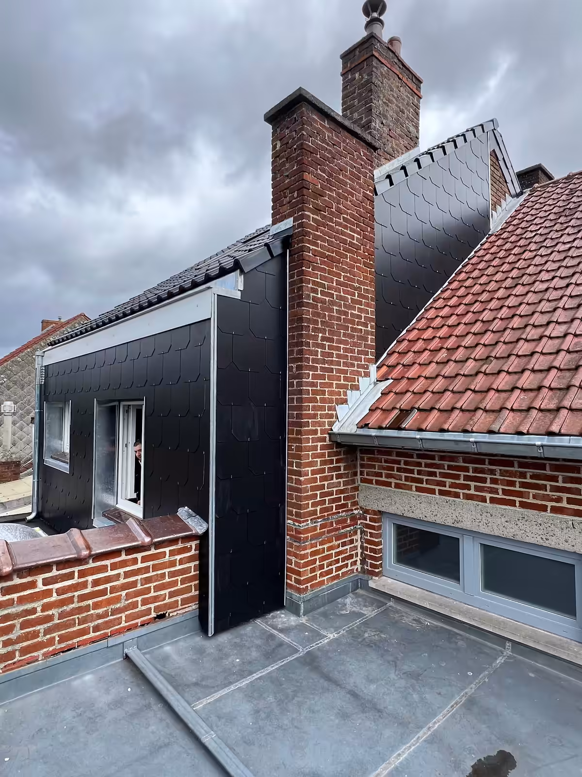 Chantier de toiture en cours — habillage en ardoises et cheminées, vu depuis le toit